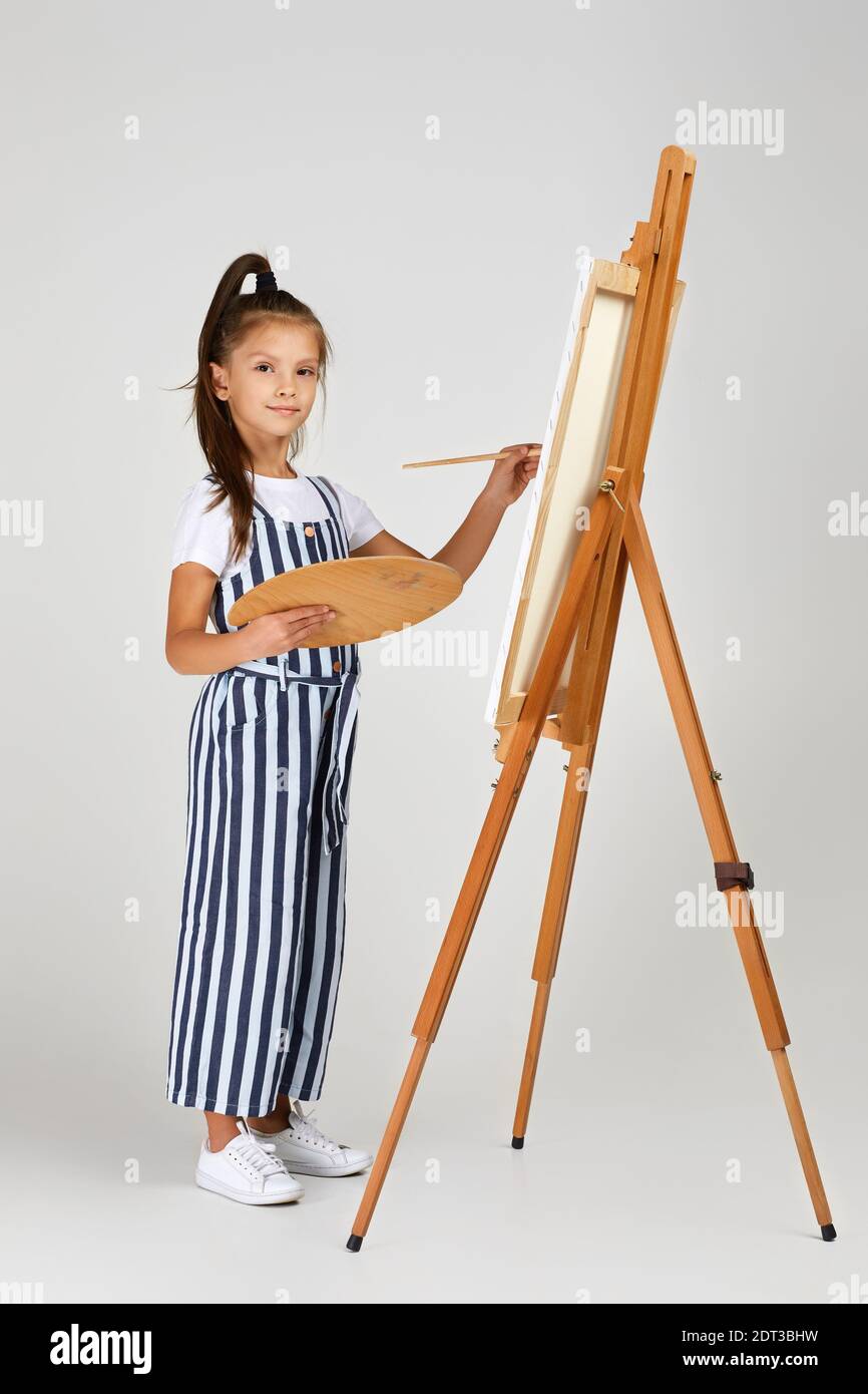 cute little girl holding a wooden art palette and brush on studio ...