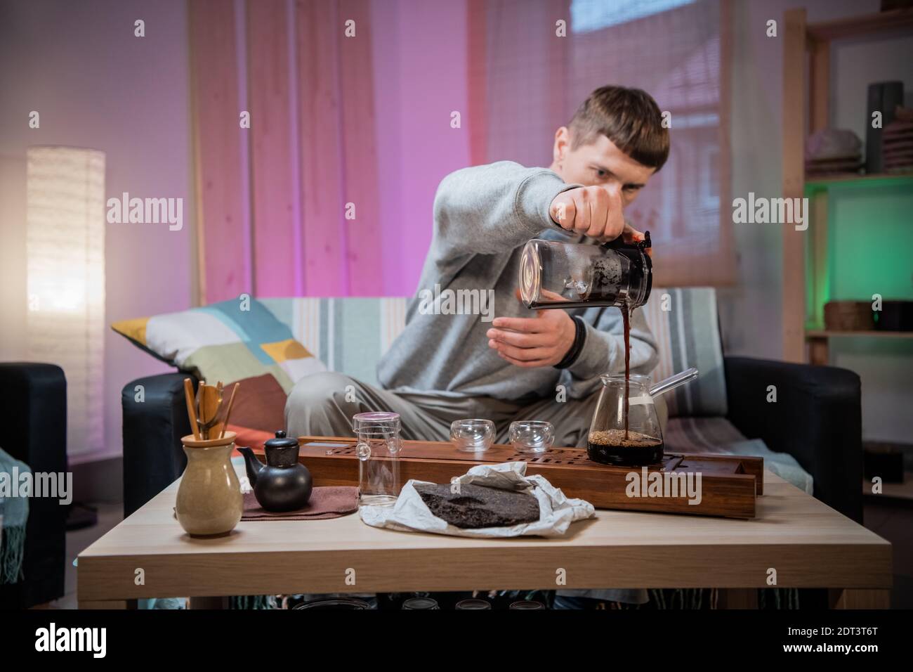 A young man is introduced to the Chinese culture of tea drinking. Brews fragrant raw tea at home. Pour boiling water over tea leaves Stock Photo