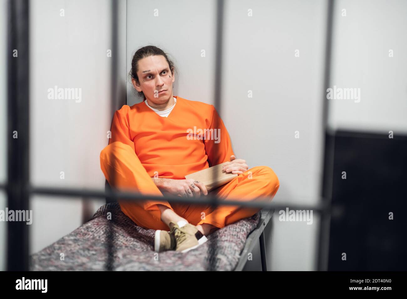 A young inmate with a tattooed face is being remotely trained in a cell ...