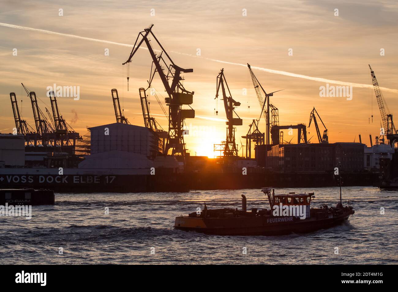 Die untergehende Sonne scheint hinter KrŠnen auf der Werft von Blohm + Voss, aufgenommen von der LandungsbrŸcken im Hamburger Hafen. Stock Photo