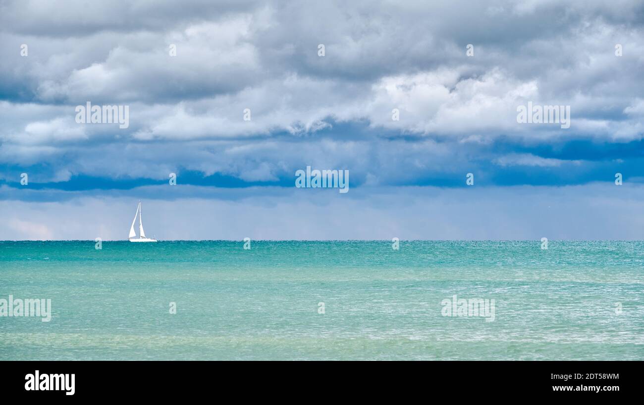 Single Sailboat close to Venice, with calm sea before the storm, under a heavy cloudy sky Stock Photo