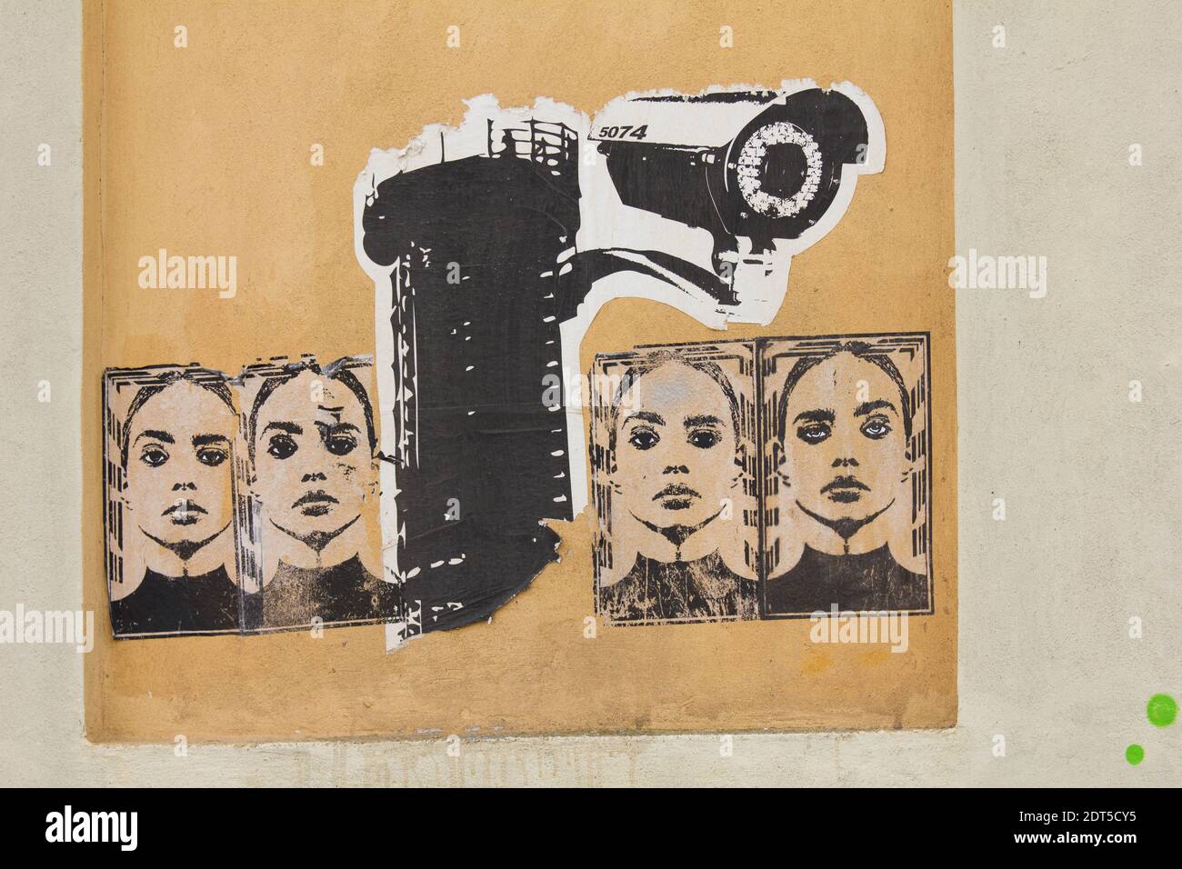 Graffiti cut outs pasted on a wall depicting a surveillance camera and female Stock Photo