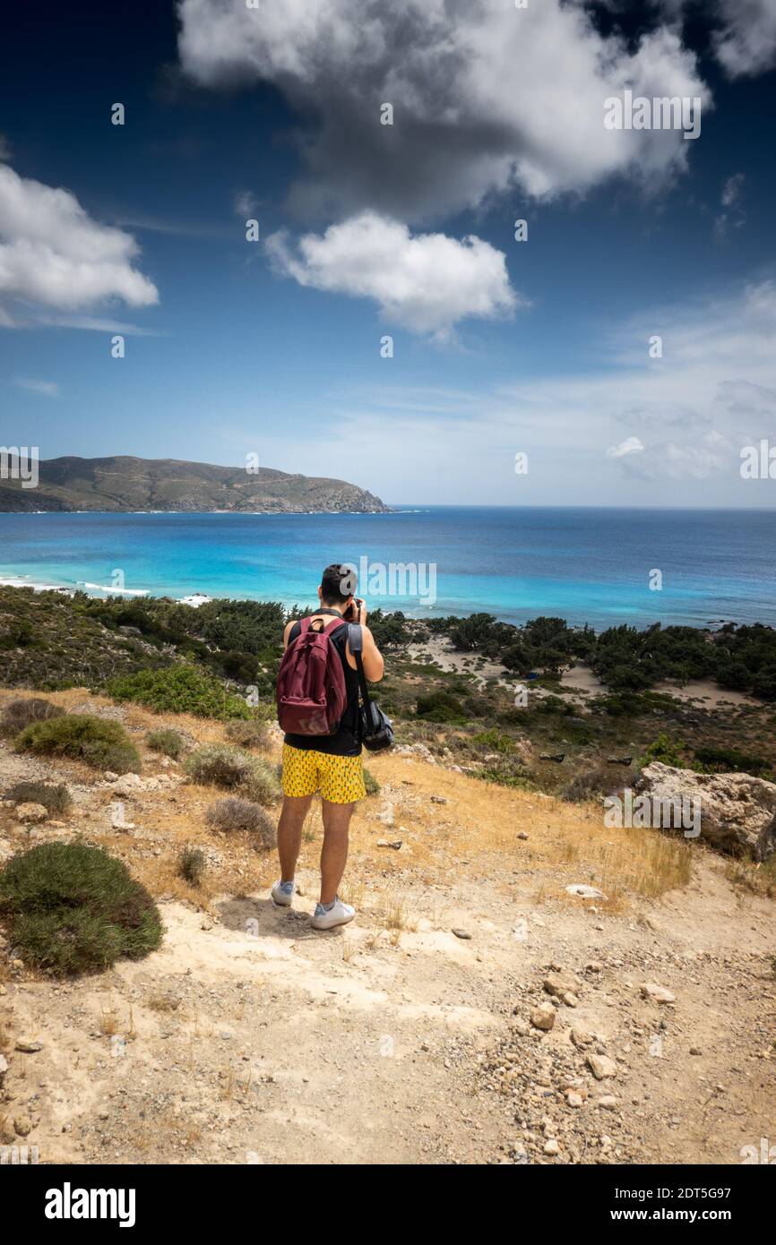 Rear view of young man photographing sea and mountain Stock Photo