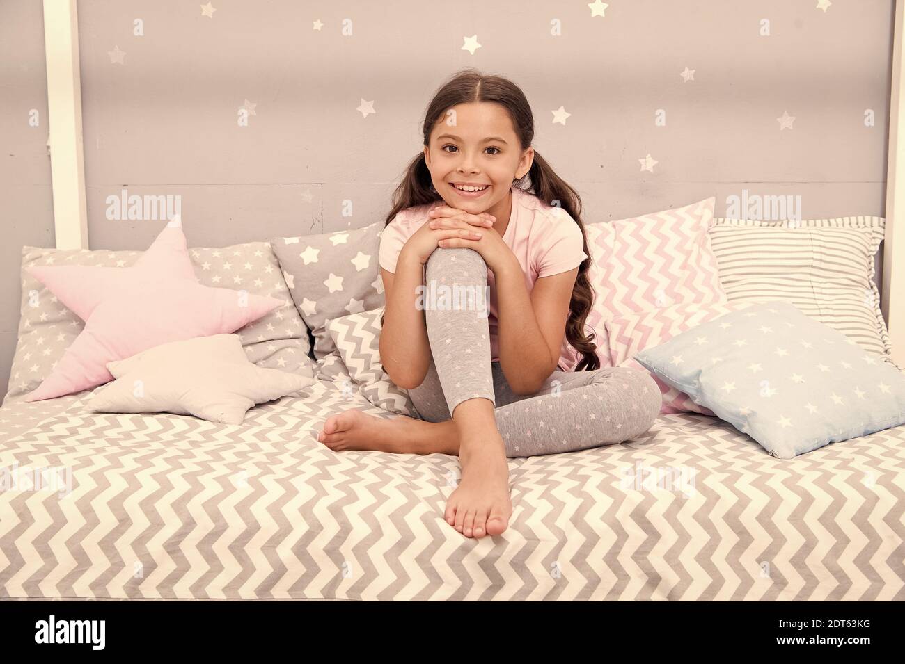 Comfortable and cozy. Little child feel comfortable at home. Small girl sit in bed. Cute kid wear comfortable pajamas. Comfortable home atmosphere. Bedtime routine. Home clothing. Fashion and beauty. Stock Photo