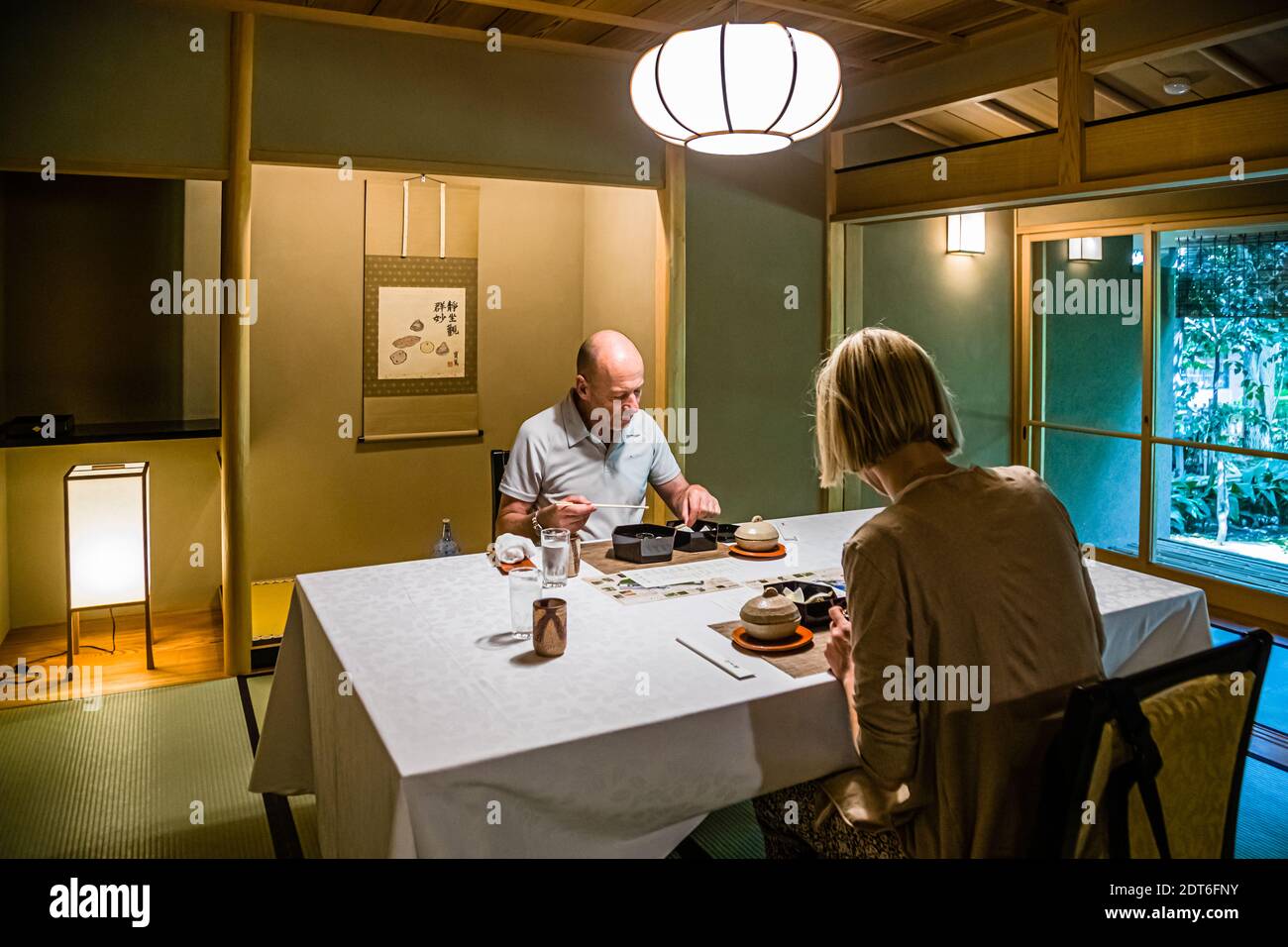 Two guests (Georg Berg and Angela Berg) sit at a set table in the traditional dining room of the Fugetsuro restaurant in Shizuoka, Japan – the former residence of the last shogun, Tokugawa Yoshinobu. Stock Photo
