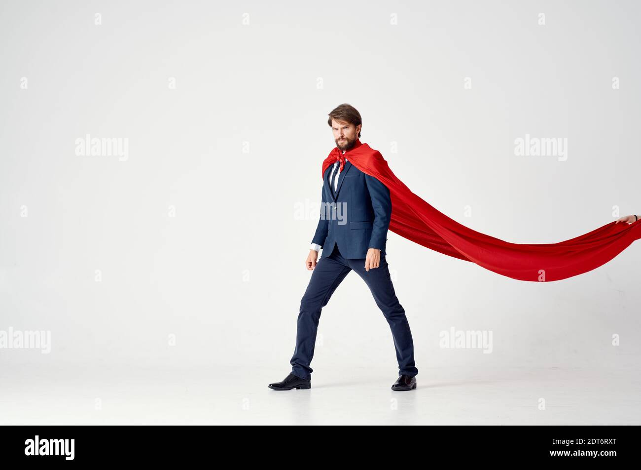 business man in a red cloak on a light background looks to the side ...
