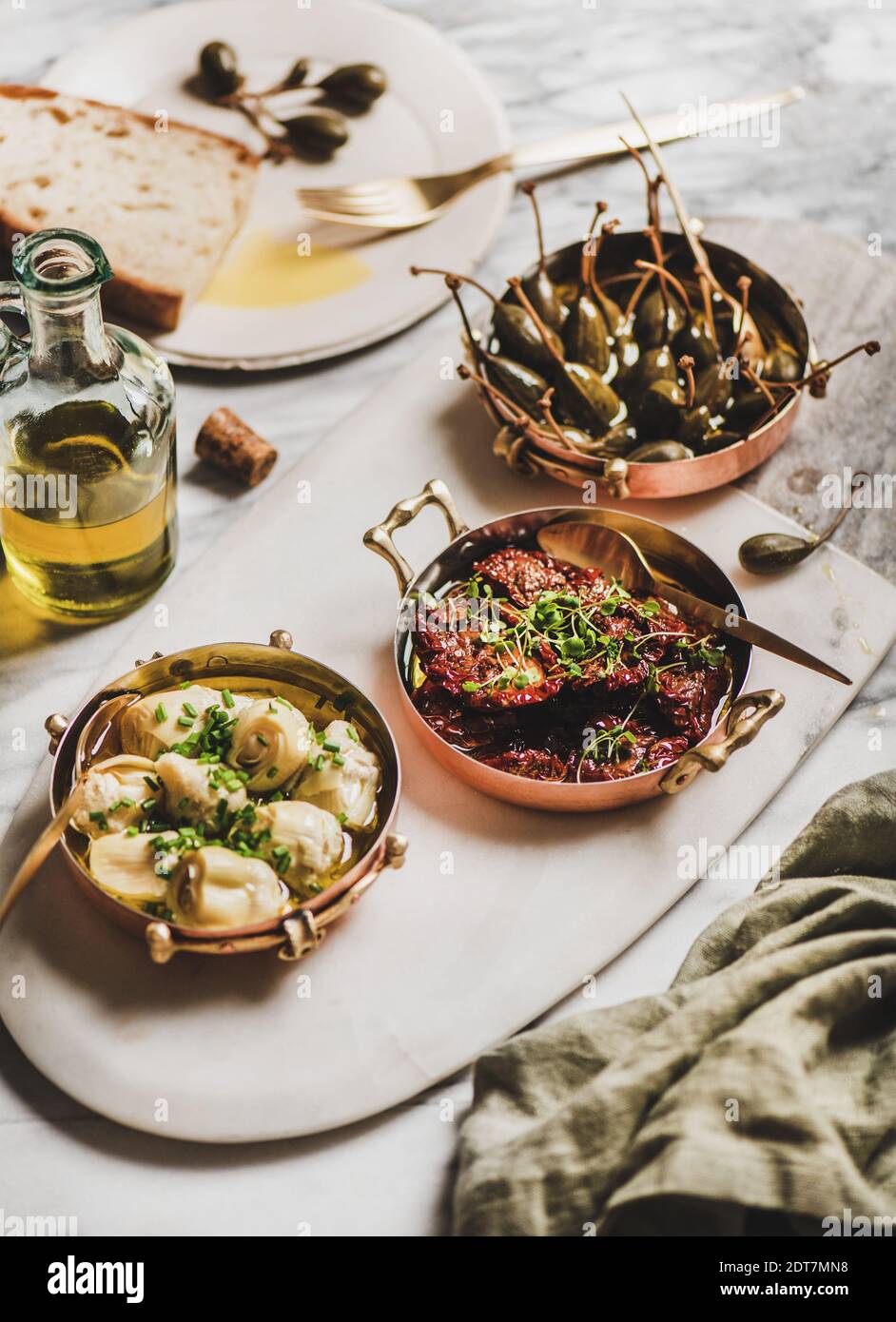 Various Mediterranean vegetarian meze in copper dishes, olive oil and fresh bread over marble table background, selective focus. Aegean cuisine concept Stock Photo