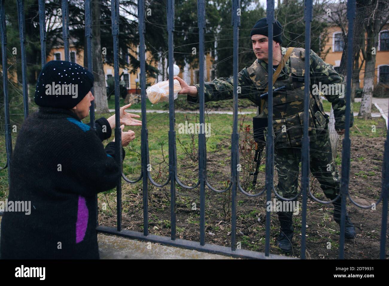 A woman gives food to a Ukranian soldier standing guard inside the Ukranian base in Simferopol. Simferopol, Ukraine, on March 19, 2014. Tensions are rising in Crimea after pro-Russia forces seized two naval bases including Ukraine's navy HQ. Russia has called on authorities there to release the detained commander of the Ukrainian navy. Photo by Rafael Yaghobzadeh/ABACAPRESS.COM Stock Photo