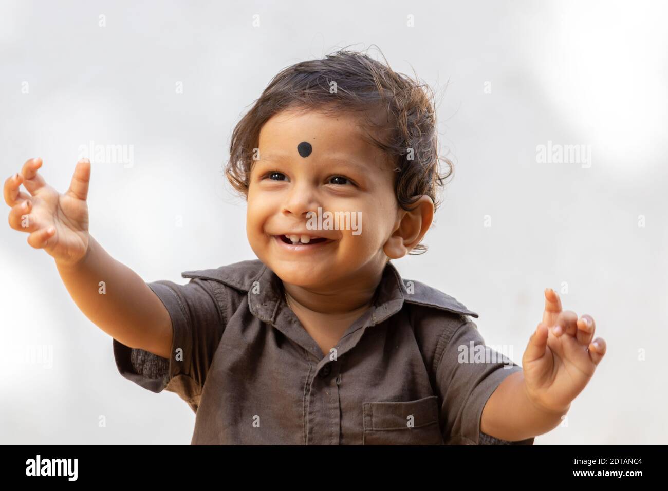 1 year old birthday boy arm raised with a dot in his forehead smiling , happiness of the kids concept. Stock Photo