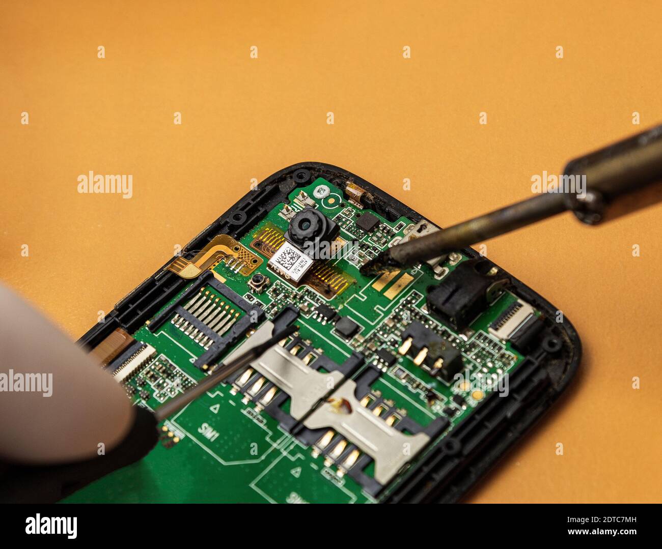 Repairing a mobile phone with a soldering iron and screwdriver Stock