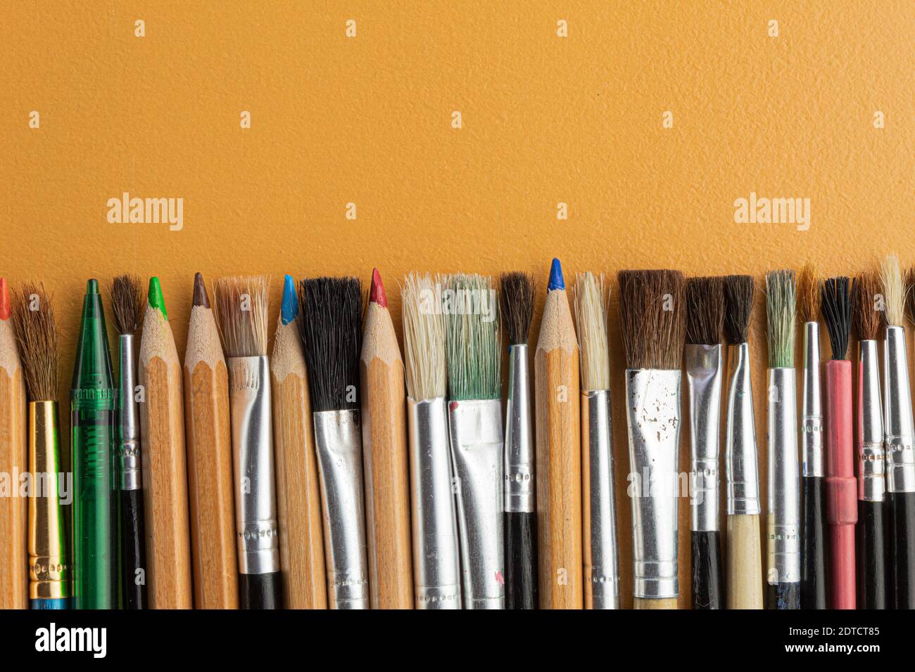 Pencils and brushes in the artist's workshop on the table. Blank for text. Stock Photo