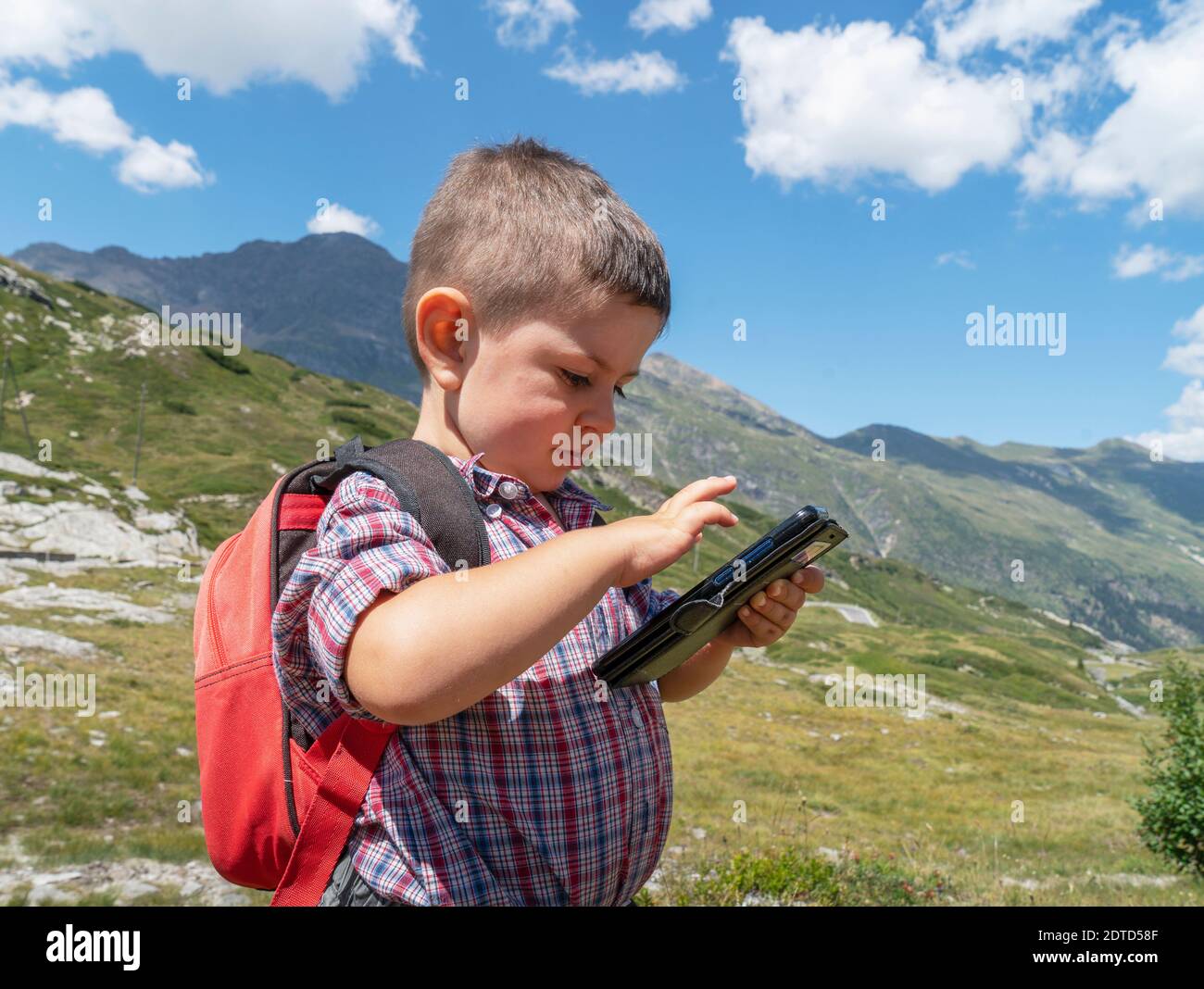 Switzerland, Canton Wallis, Zermatt, Boy with smartphone hiking in mountains Stock Photo