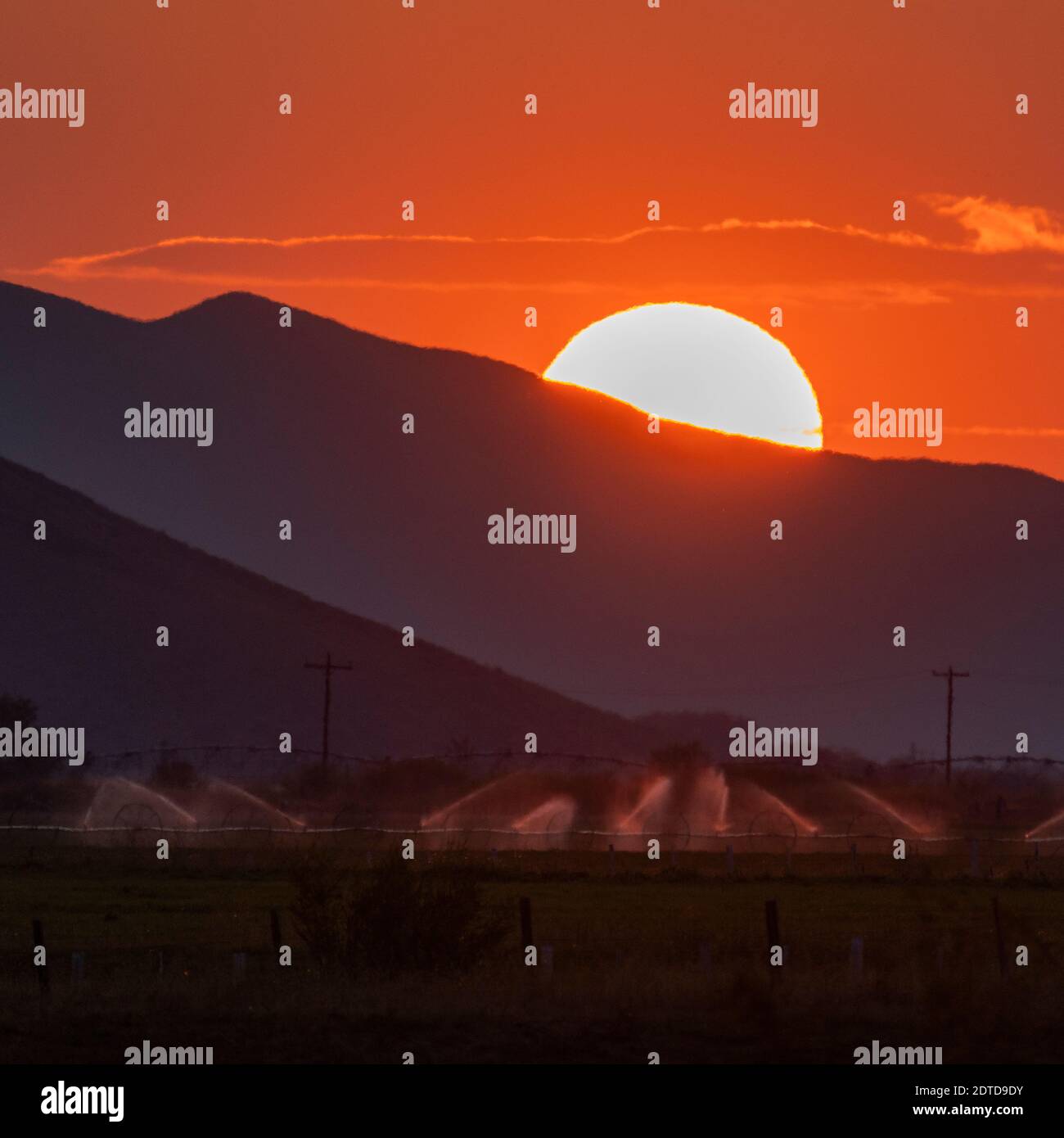 USA, Idaho, Bellevue, Irrigation equipment in field and sun setting behind mountain Stock Photo