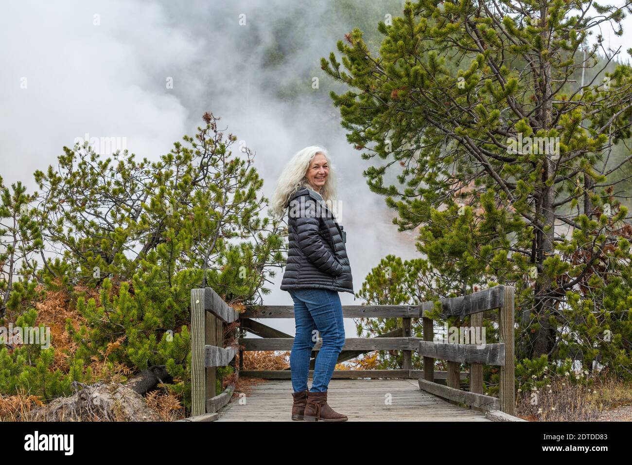USA, Wyoming, Yellowstone National Park, Senior female tourist standing on wooden observation point in Yellowstone National Park Stock Photo