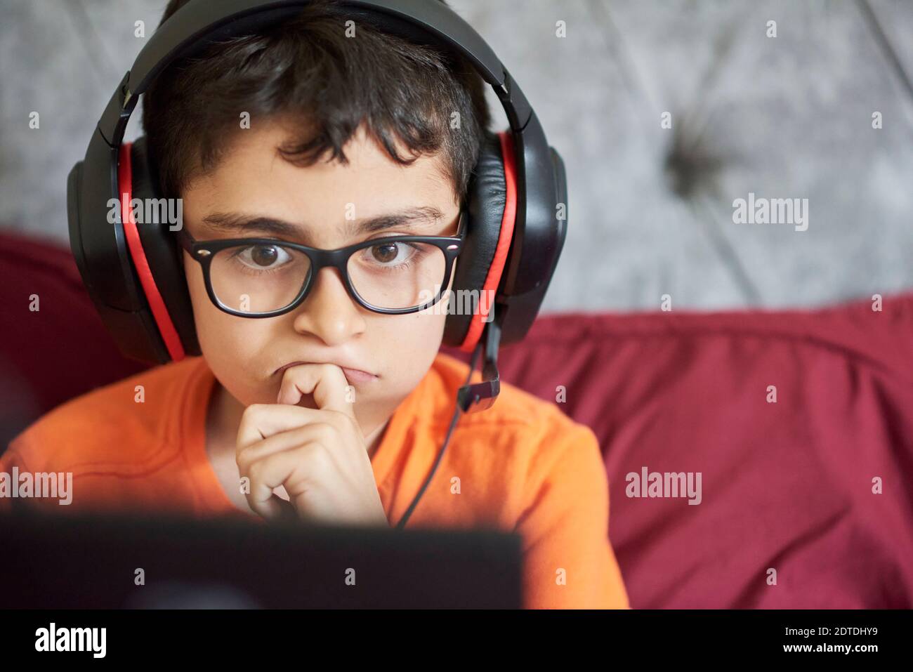 Boy (8-9) gaming on tablet while sitting in bed during weekend Stock Photo