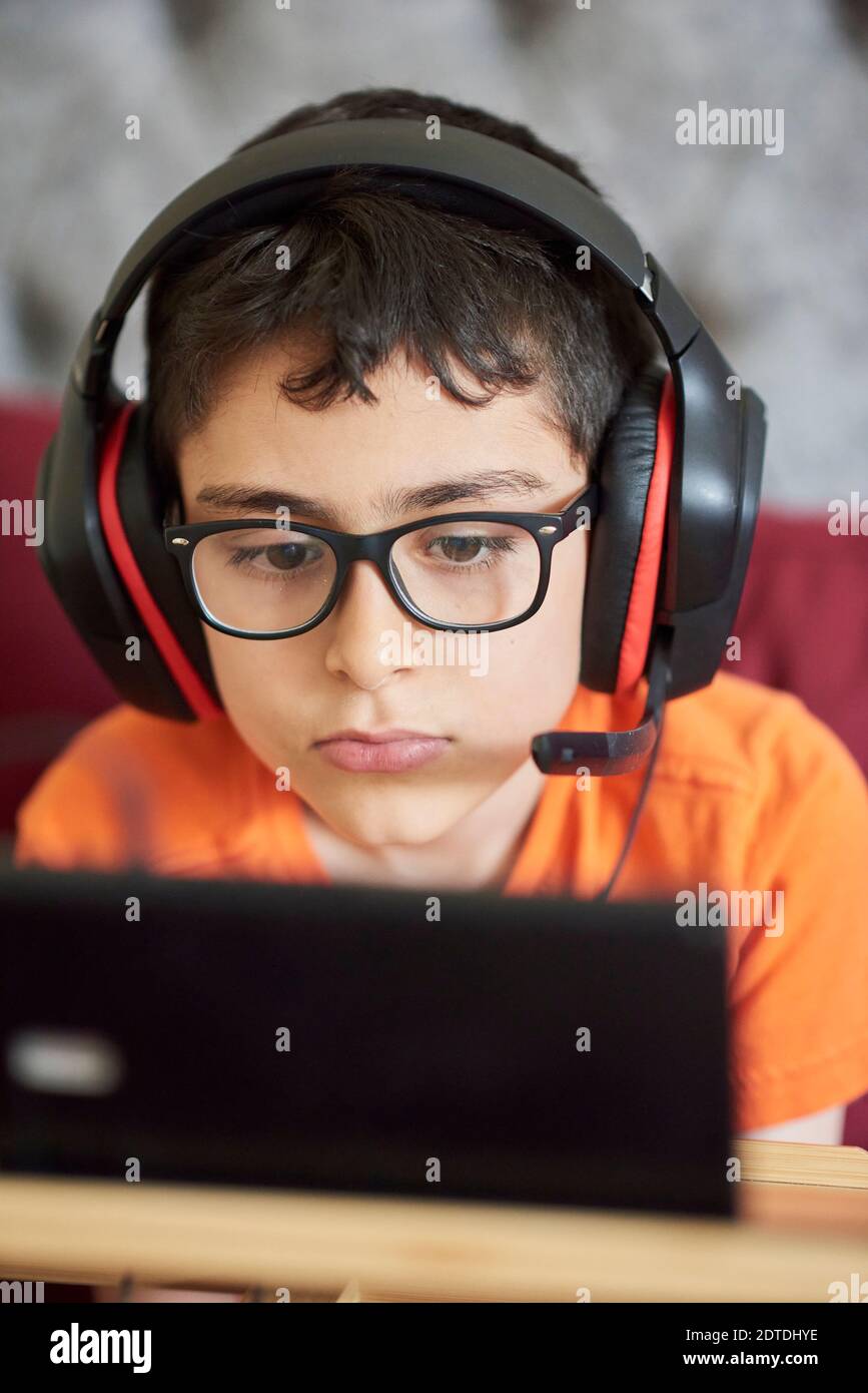 Boy (8-9) gaming on tablet while sitting in bed during weekend Stock Photo