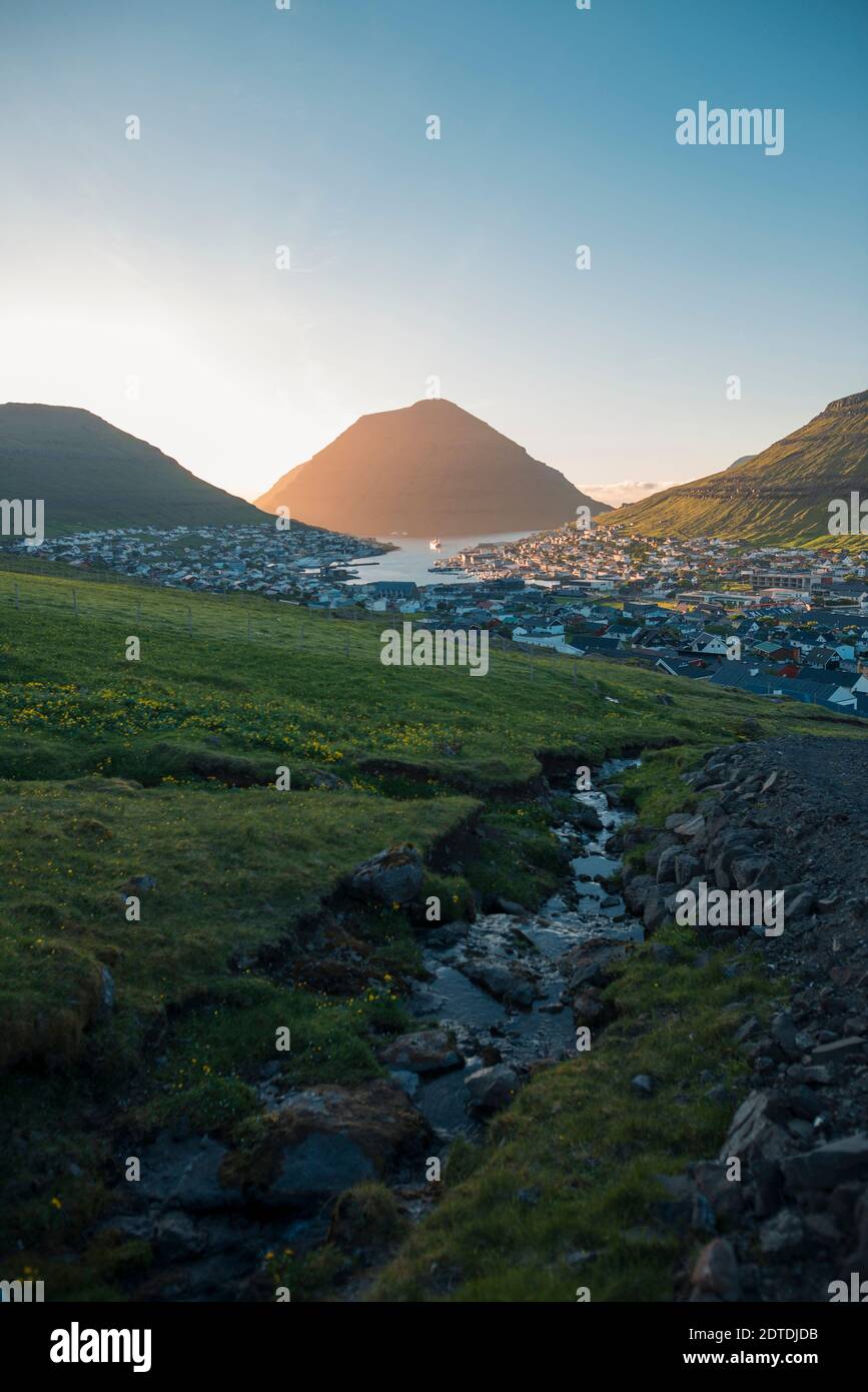 Denmark, Faroe Islands, Klaksvik, Landscape with mountains and village by sea at dawn Stock Photo