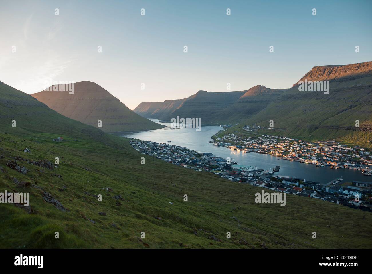 Denmark, Faroe Islands, Klaksvik, Landscape  with mountains and village by sea at dawn Stock Photo