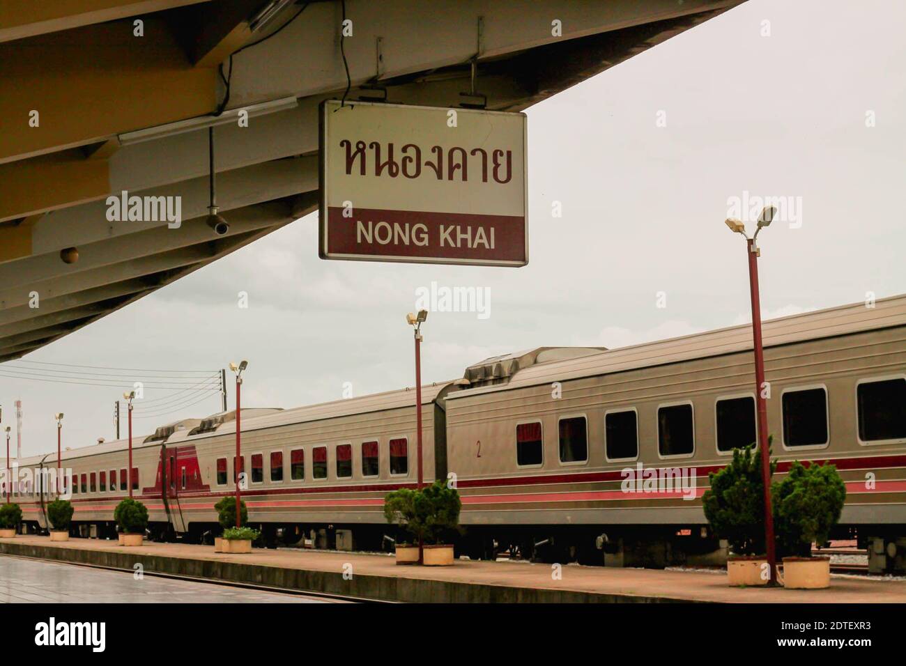 Train By Sign Hanging From Roof At Railroad Station Platform Stock Photo