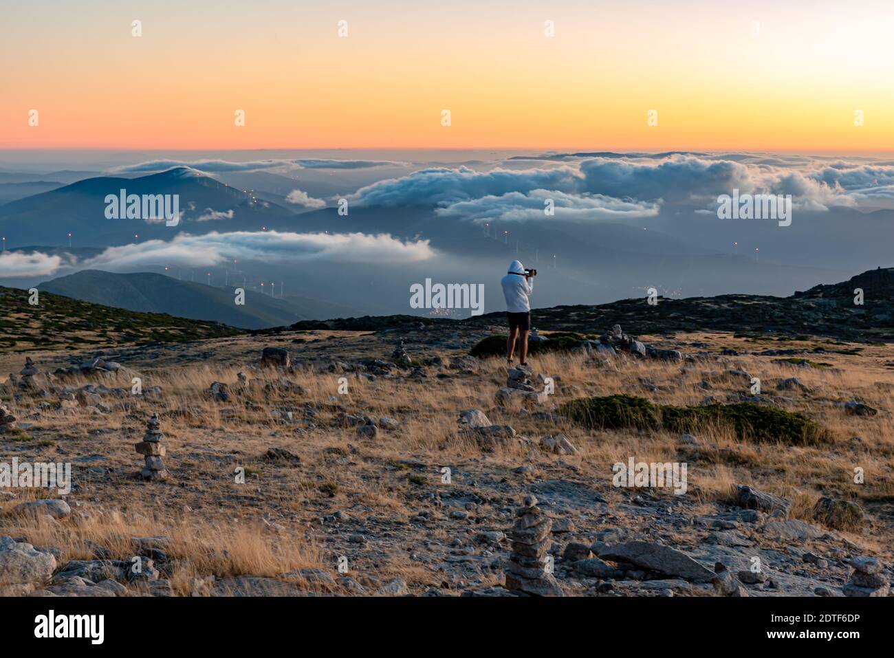 Sunset at the top of the Serra da Estrela Natural Park, Portugal with low clouds and a person watching the landscape with his camera Stock Photo