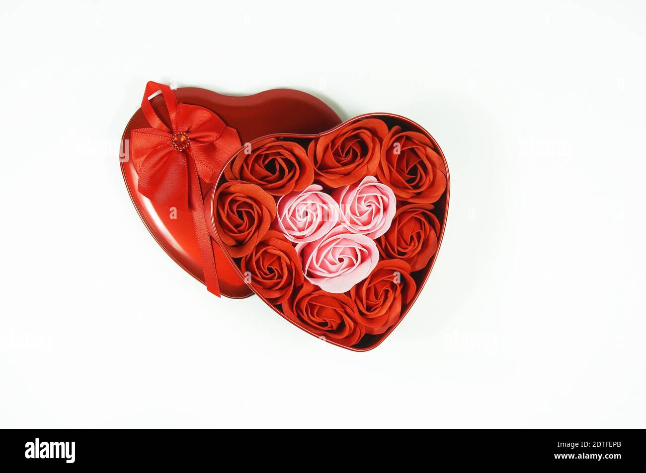 High Angle View Of Roses In Heart Shape Container Against White
