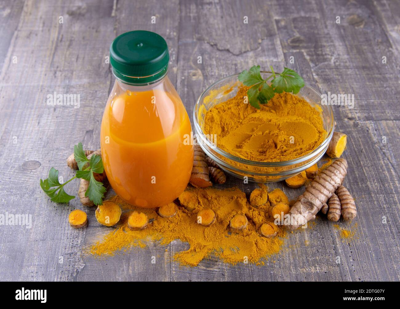 Turmeric juice in a bottle and turmeric powder on a wooden background