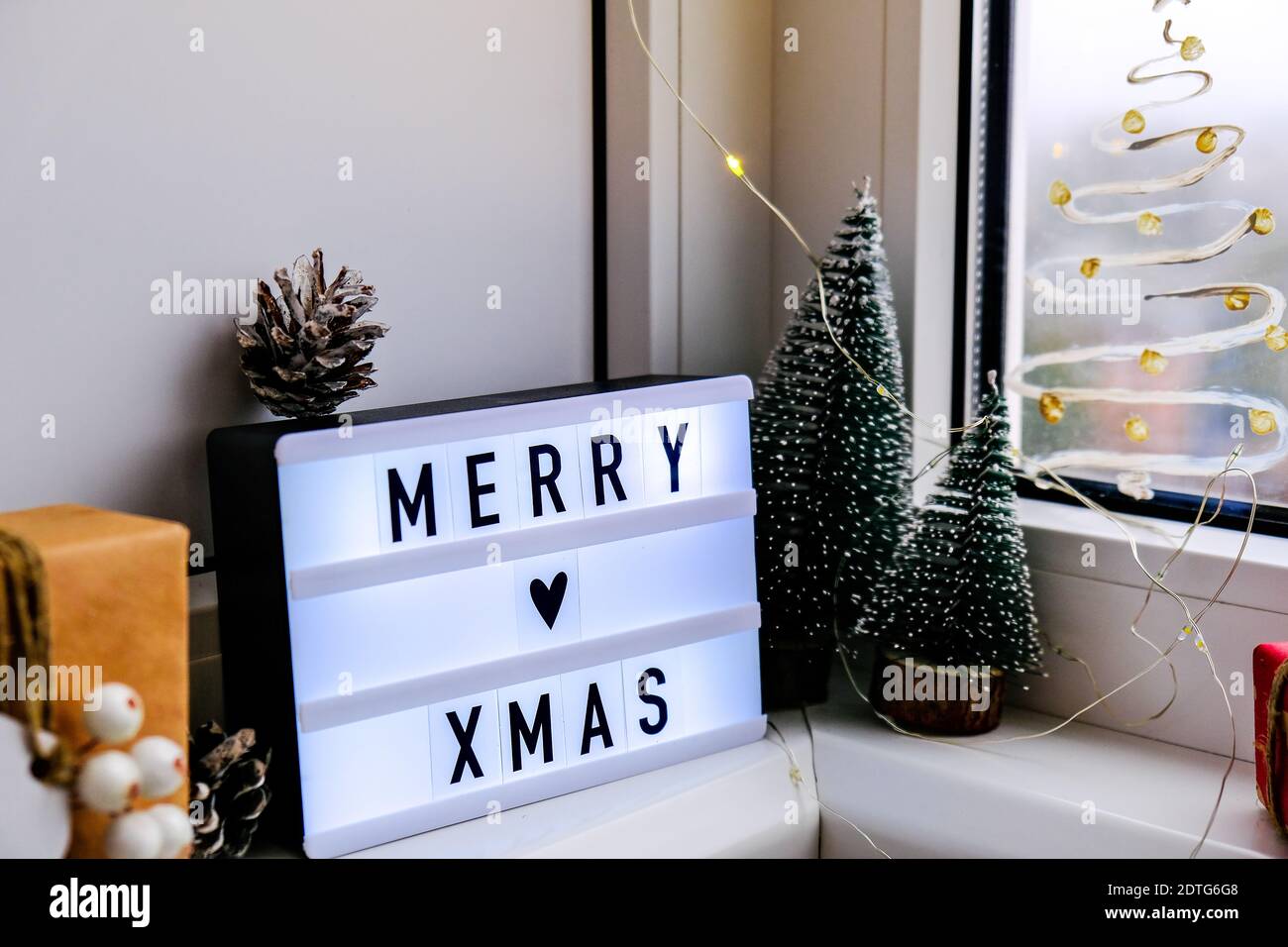 Lightbox with text MERRY XMAS christmas on windowsill. New year  decorations, garland lights and christmas trees. Window painted with snow  spray. Hygge Stock Photo - Alamy