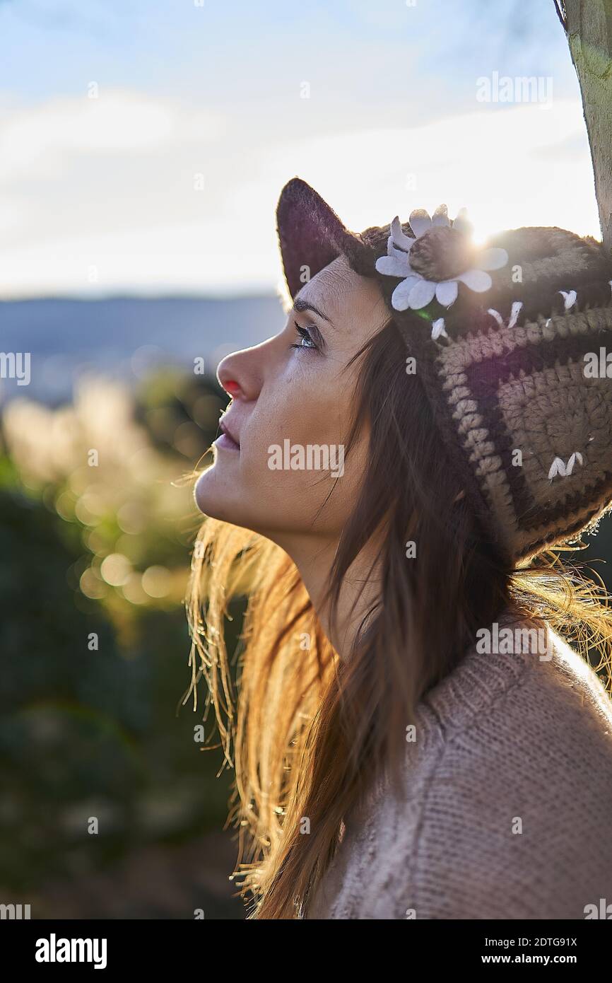 portrait of beautiful woman in profile looking up in a park in winter ...