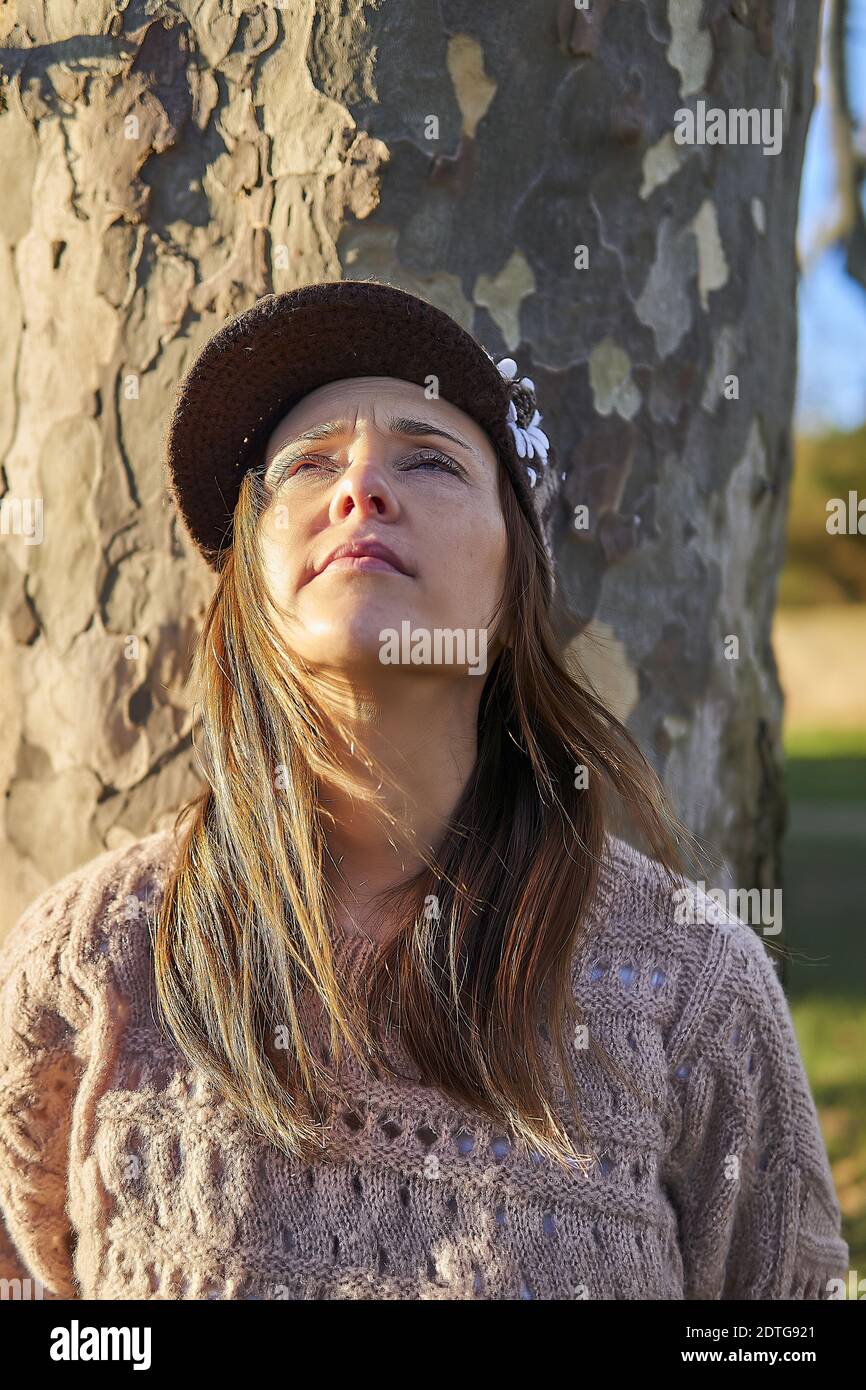 portrait of beautiful woman looking up in a park in winter with sun ...