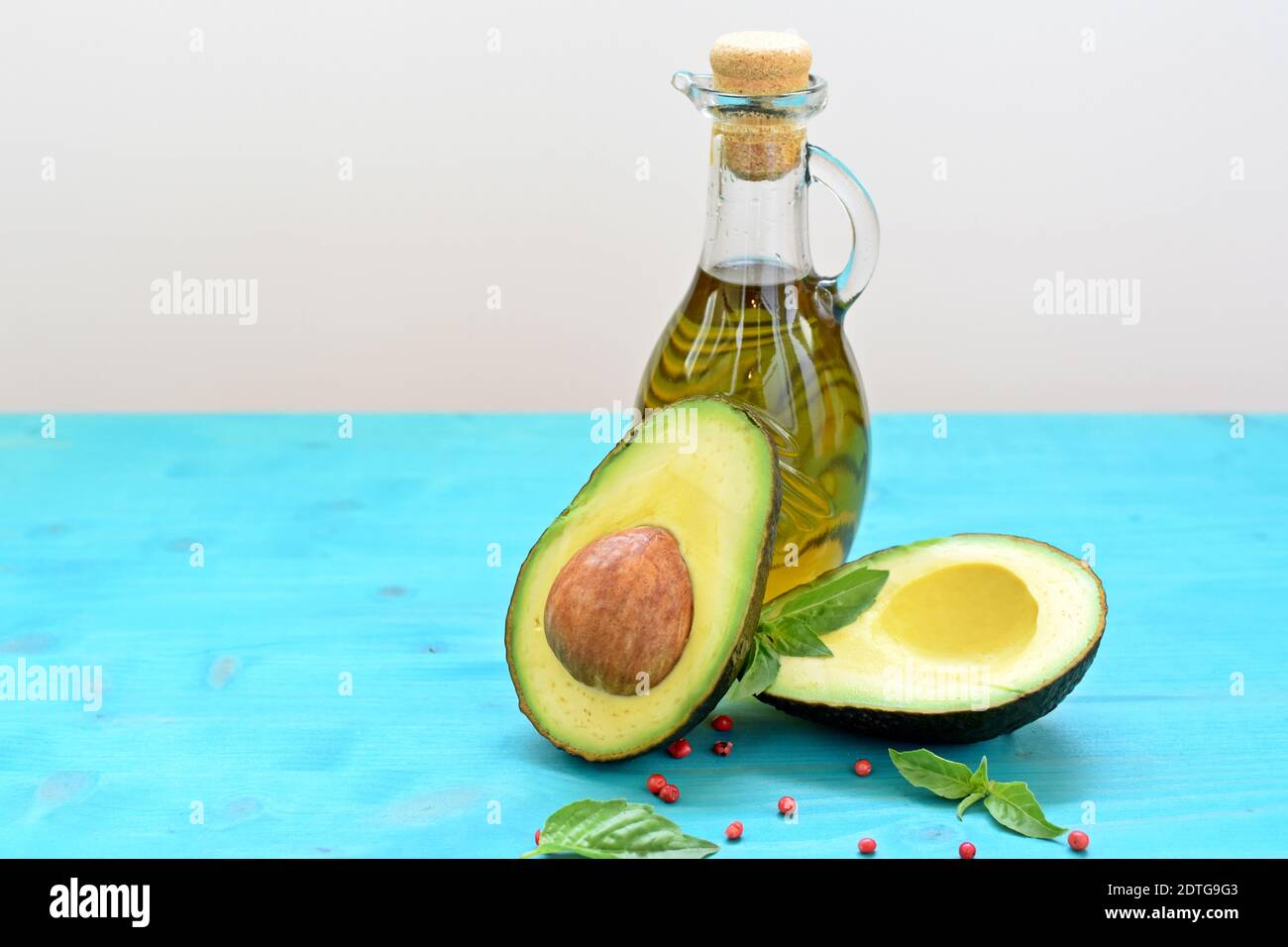 Concept of healthy food with cut avocado and a bottle of olive oil on blue and white background. Stock Photo