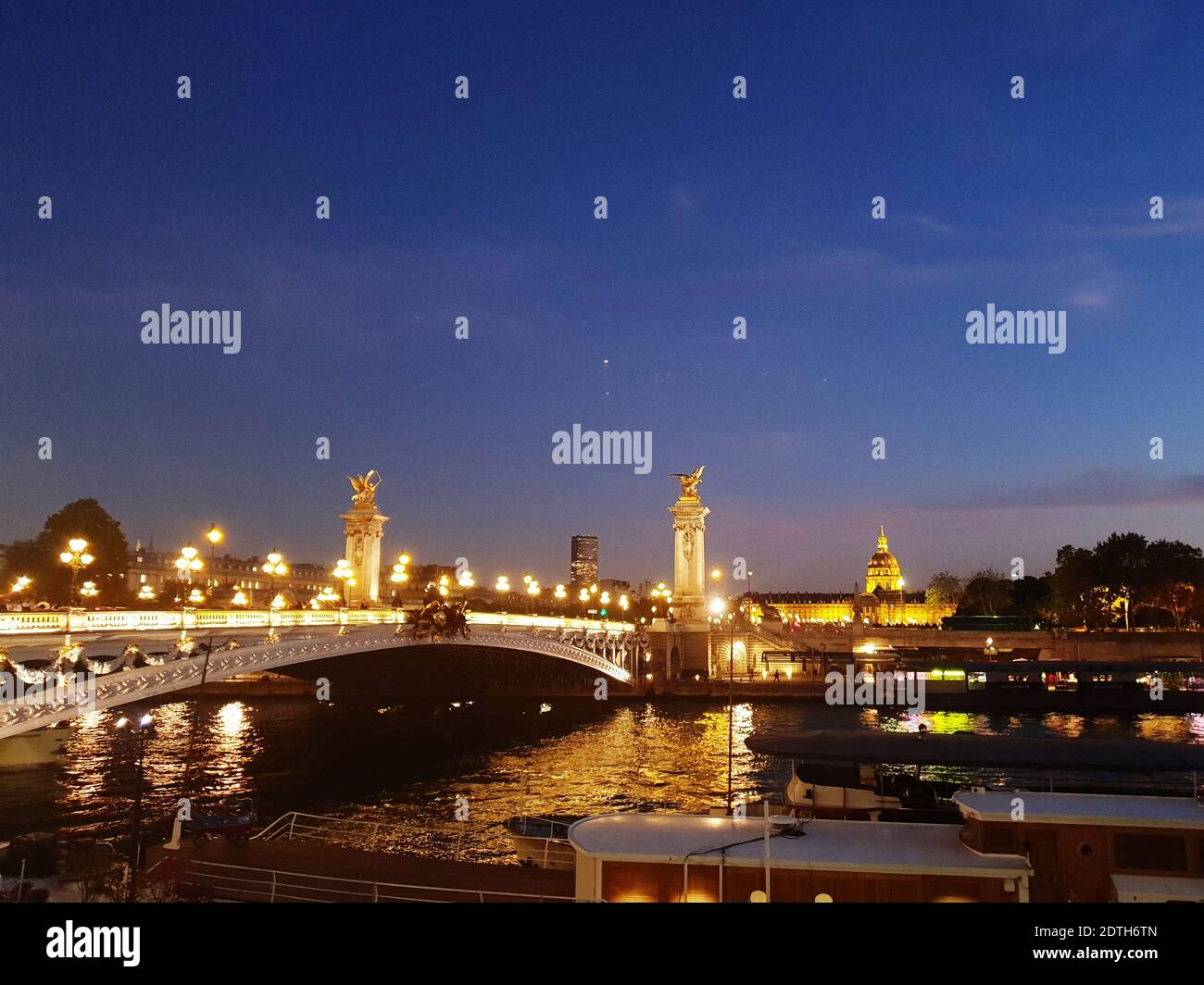 Illuminated Bridge Over River Against Sky In City At Night Stock Photo
