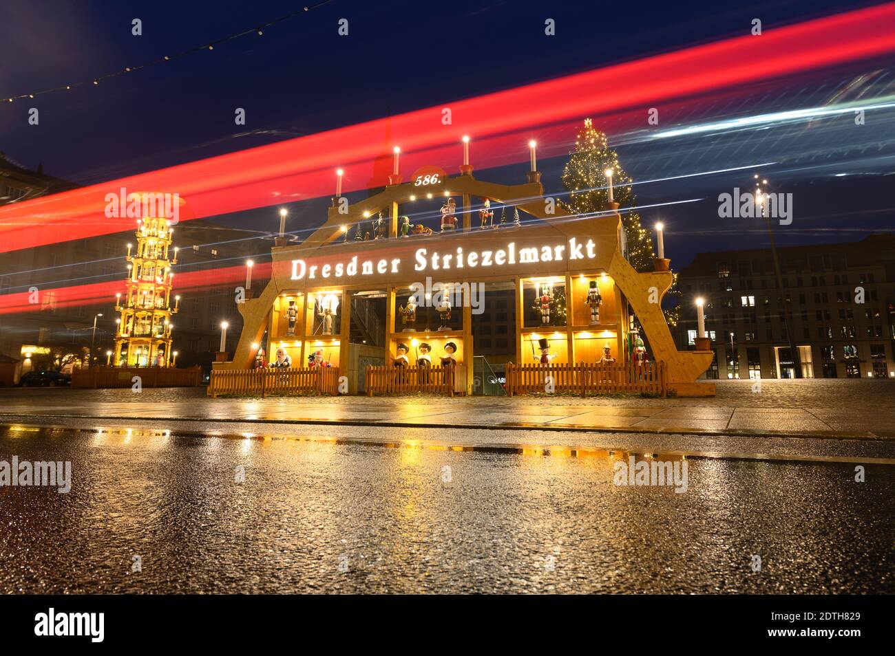 Dresden, Germany. 22nd Dec, 2020. Passing cars leave traces of light in front of an oversized candle arch and a pyramid on the deserted Altmarkt. (Long exposure shot) Germany is in a hard lockdown to contain the Corona pandemic. Credit: Sebastian Kahnert/dpa-Zentralbild/dpa/Alamy Live News Stock Photo