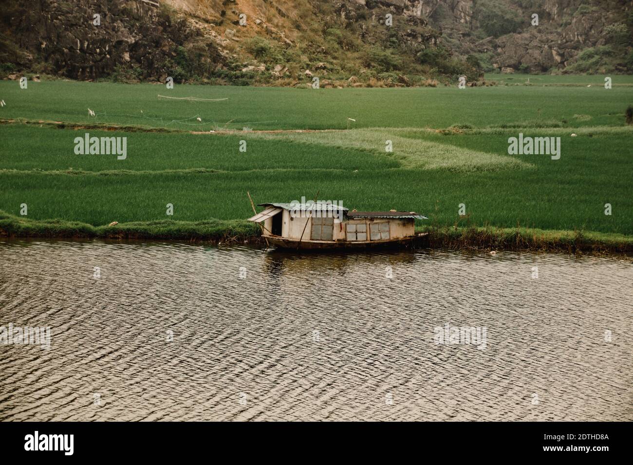 Cinematic scenery of a wooden boat house moored in the riverside of Ninh Binh, Vietnam Stock Photo