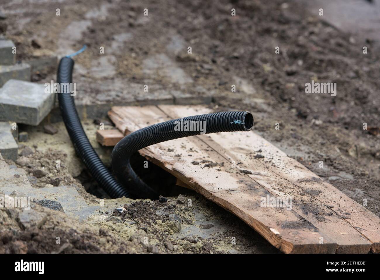 Thin diameter ribbed black PVC pipe in the ground before laying Stock