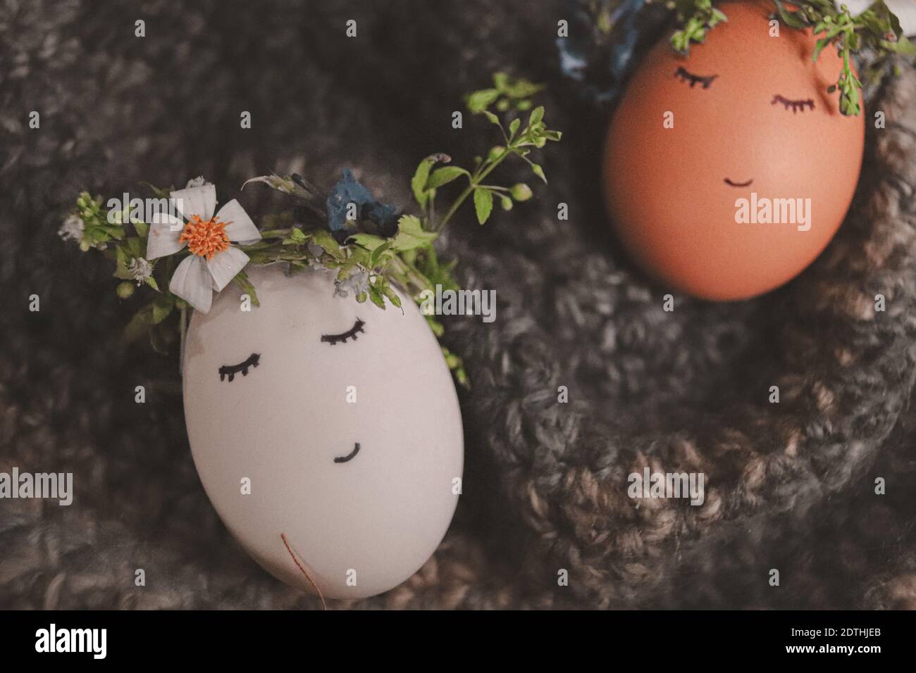 Cute eggs wearing flower crowns with drawn faces as decoration for Easter and the coming of Spring Stock Photo