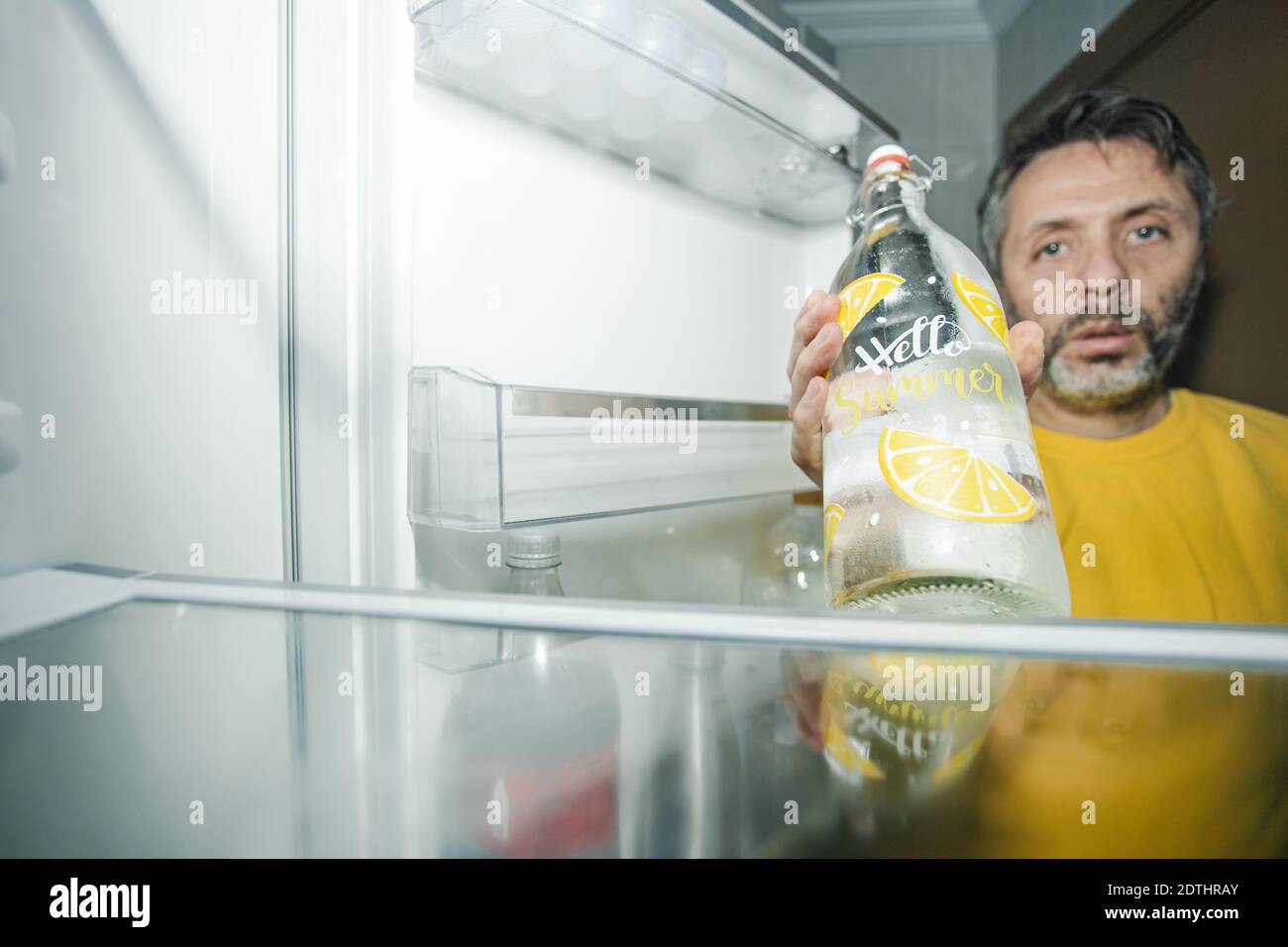 https://c8.alamy.com/comp/2DTHRAY/middle-age-male-demonstrating-a-glass-bottle-with-water-to-camera-while-standing-near-open-door-of-empty-refrigerator-2DTHRAY.jpg