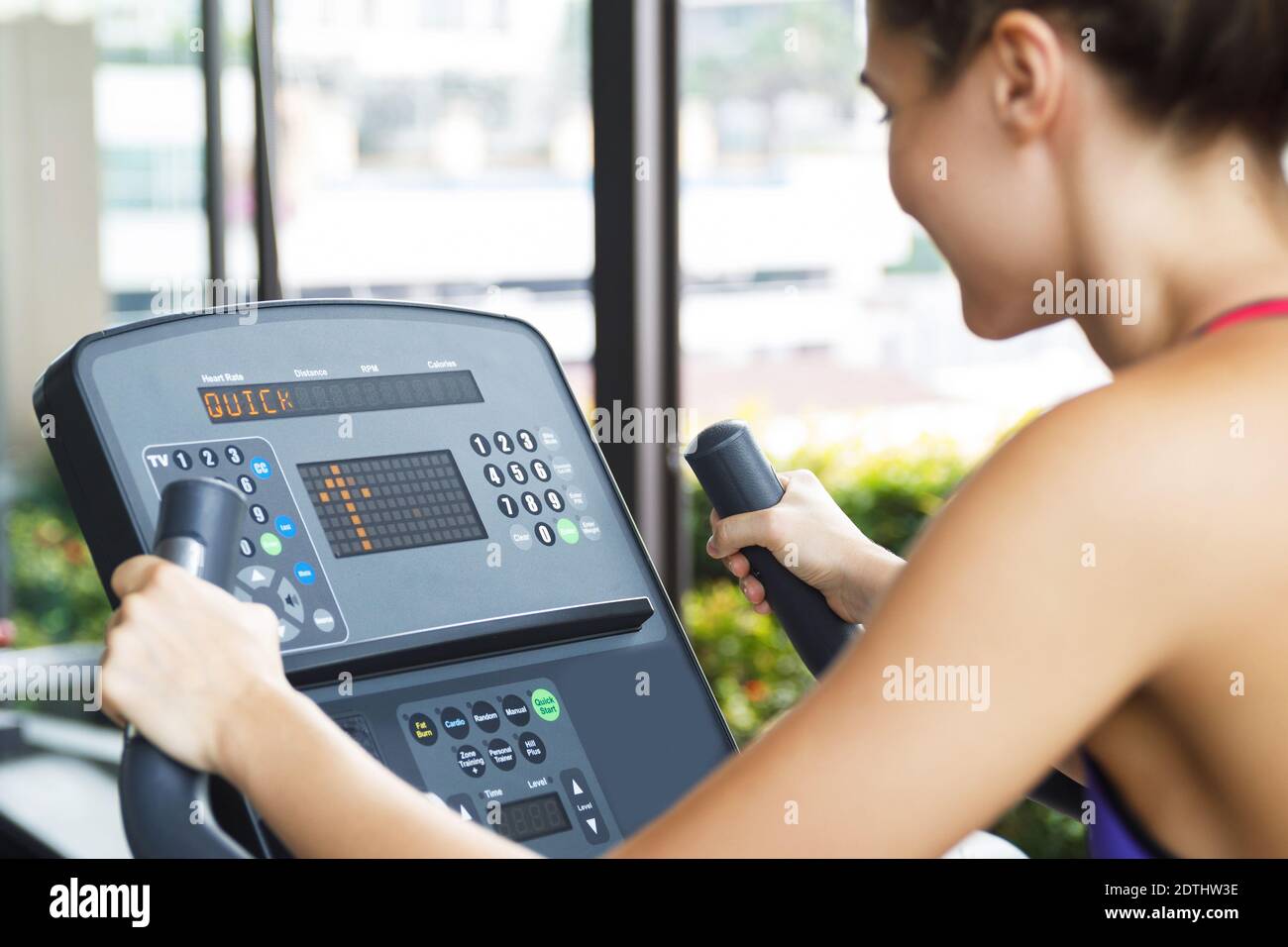 Fitness workout on stationary bike in the gym. Woman is setting up the