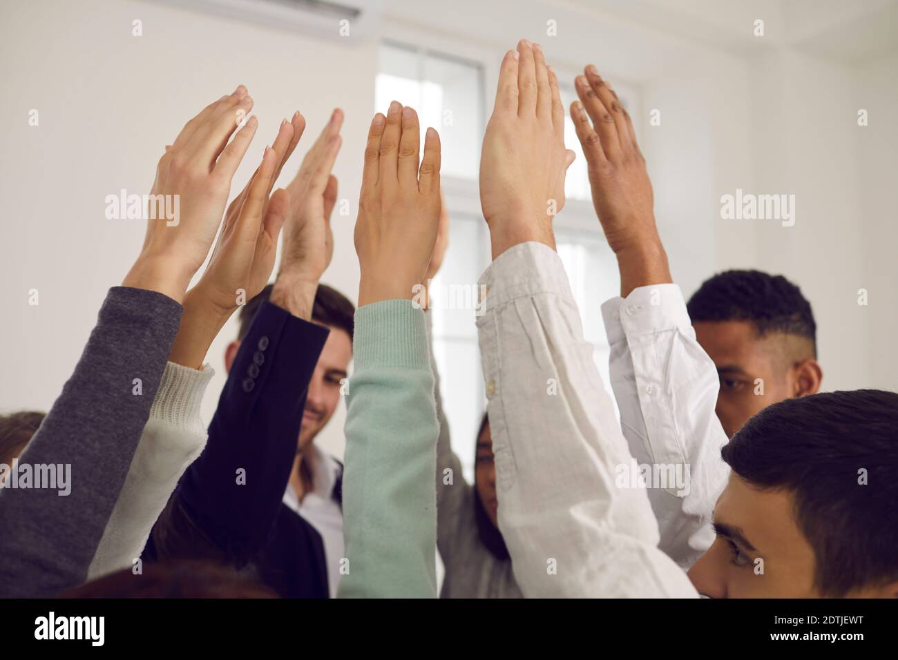 Team of young people raising hands up in the air, voting for good idea or showing solidarity Stock Photo