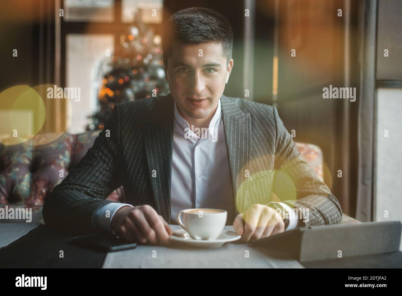A young and attractive man uses his tablet while drinking coffe in an indoor restaurant Stock Photo