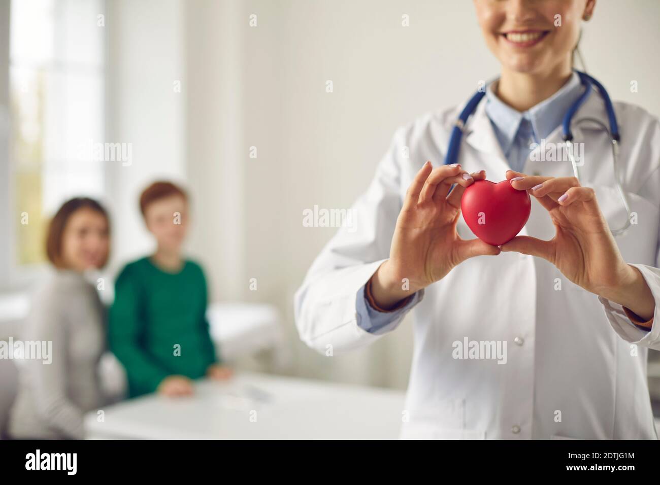 Family doctor holding red heart, promoting healthy lifestyle and disease prevention Stock Photo