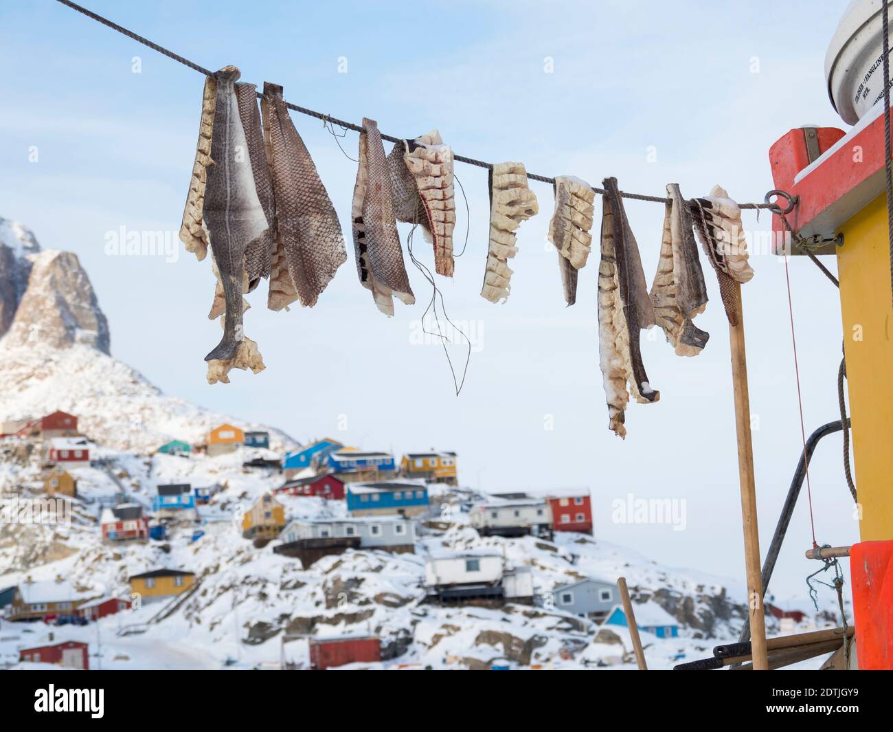 Town Uummannaq during winter in northern Greenland. Ship with drying fish in the frozen harbour. America, North America, Denmark, Greenland Stock Photo