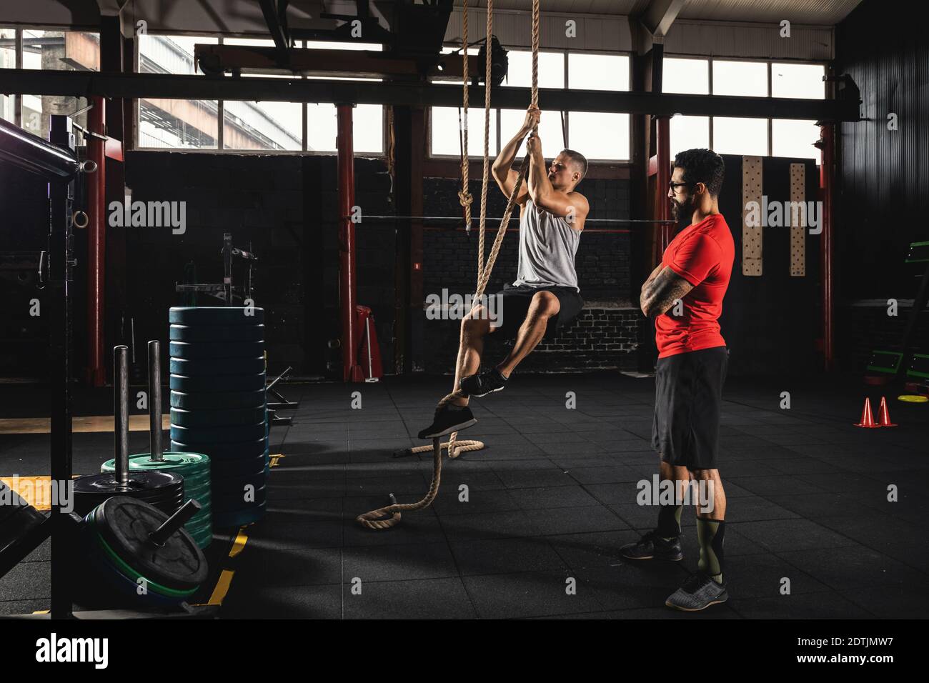 Rope climbing exercise. Sportsman and his trainer during workout in the