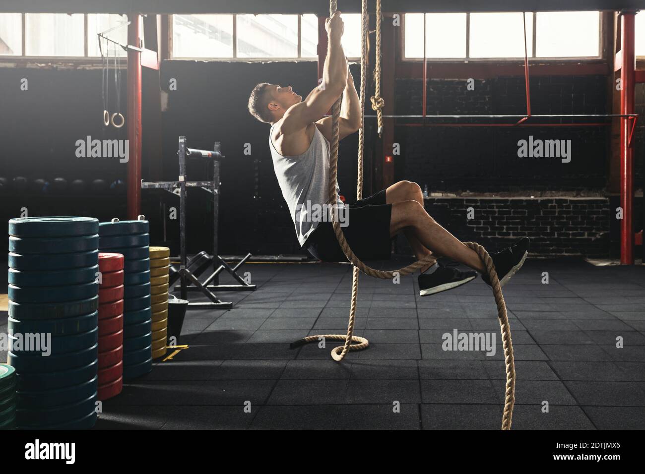 Rope climbing exercise. Sportsman during his cross training workout
