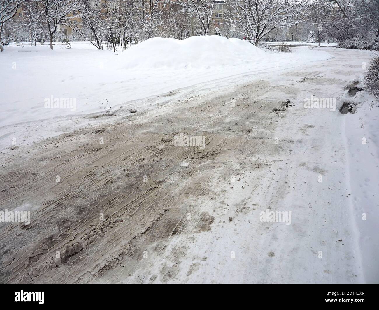 Roadway is covered with a thick layer of dirty loose snow in winter Stock Photo