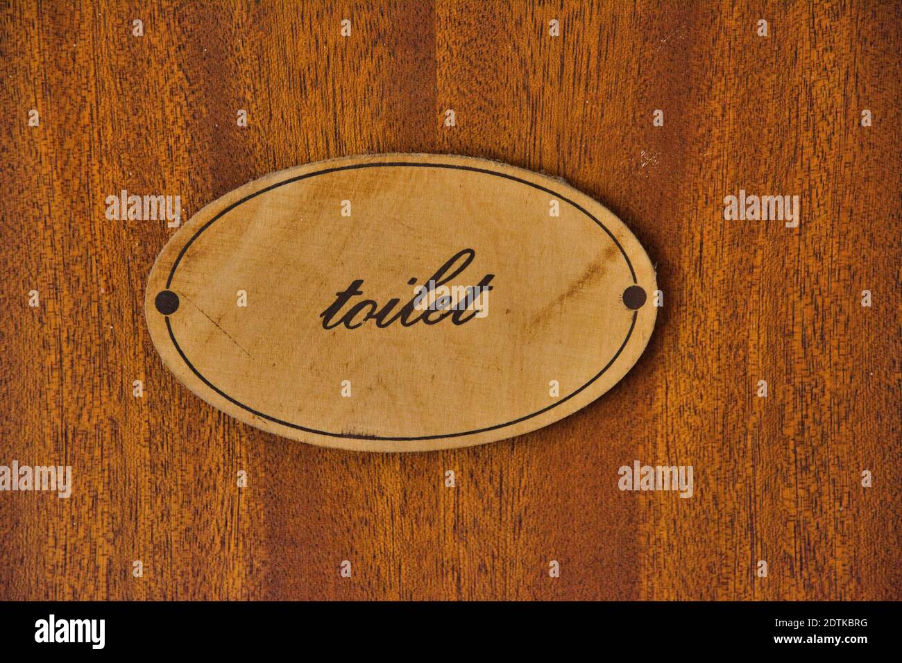 A closeup of the signage with the word "toilet" posted on the wooden