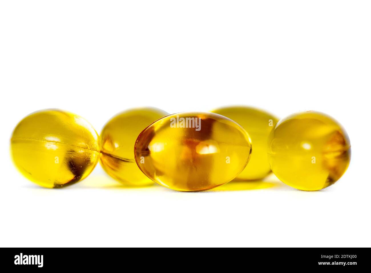 Yellow capsules of vitamin D, macro close-up of golden pills isolated on white Stock Photo