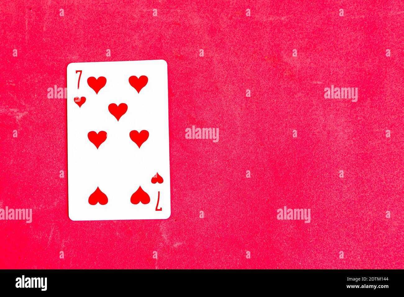 Seven of Hearts playing card, red background, copy space Stock Photo