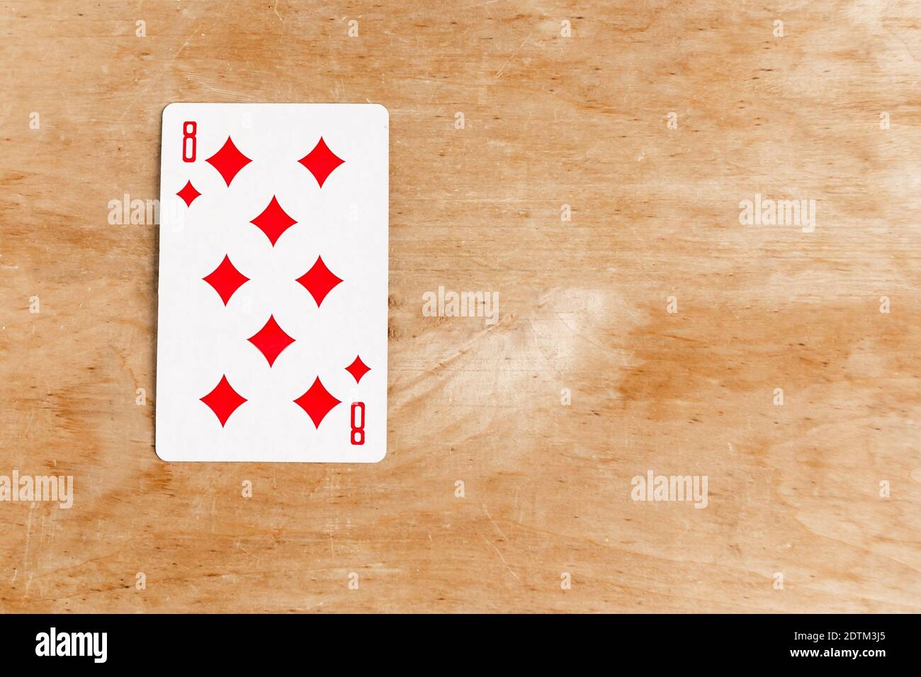 Eight of Diamond playing card, wooden background, copy space Stock