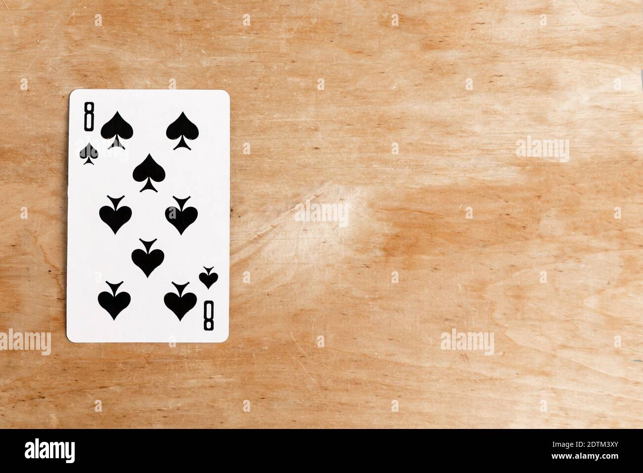 Eight of Spades playing card, wooden background, copy space Stock Photo