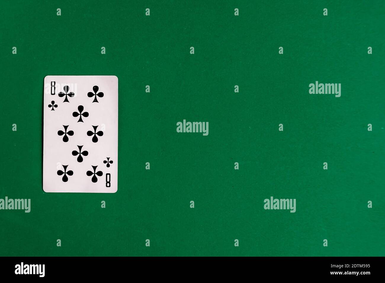 Eight of Clubs playing card, green background, copy space Stock Photo